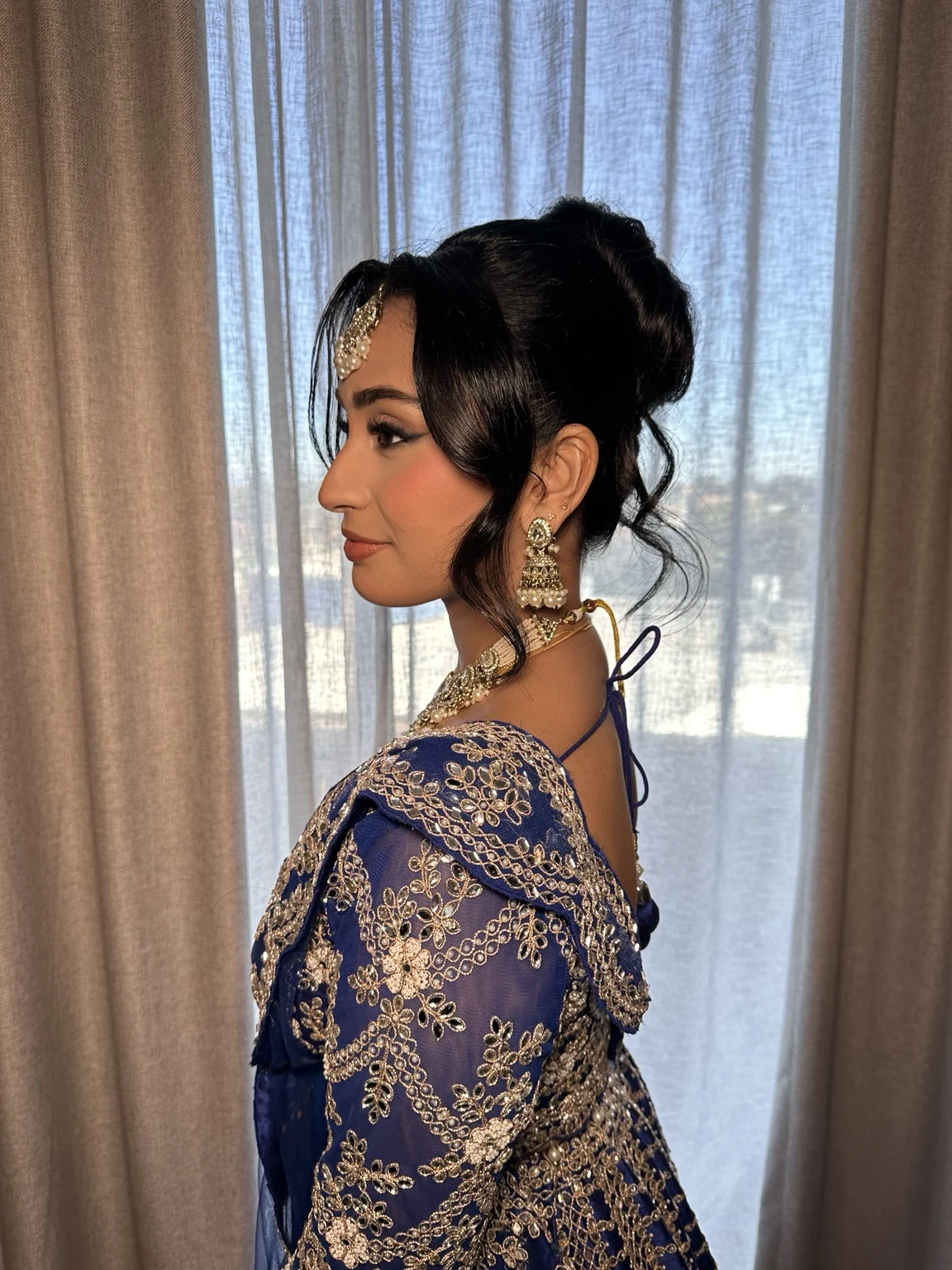 Avishma’s reception updo in profile, with sculpted waves around her face and bridal jewellery