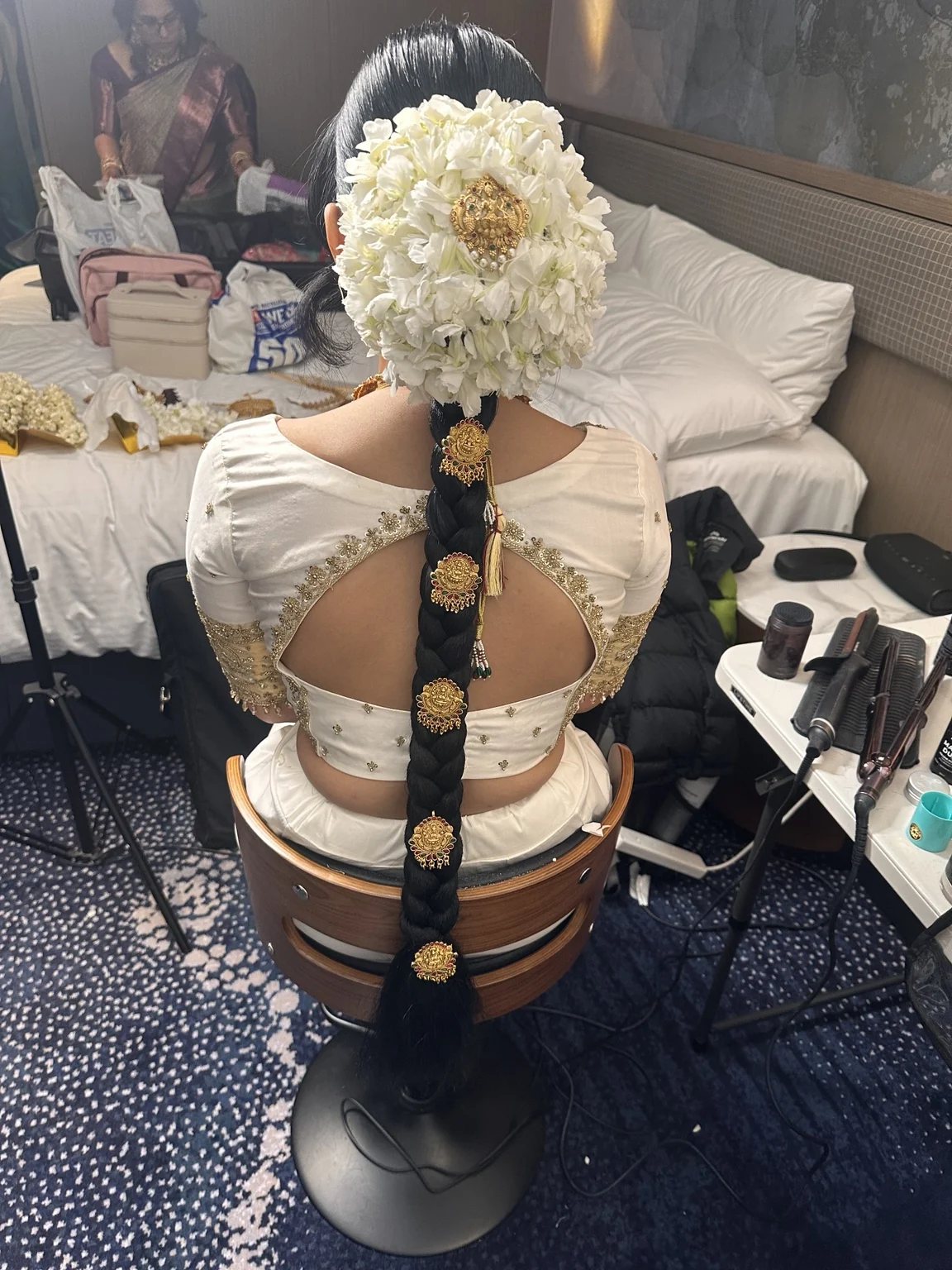 The back of Avishma’s wedding hairstyle, a long bridal braid with white flowers and gold hair jewellery created by Heera