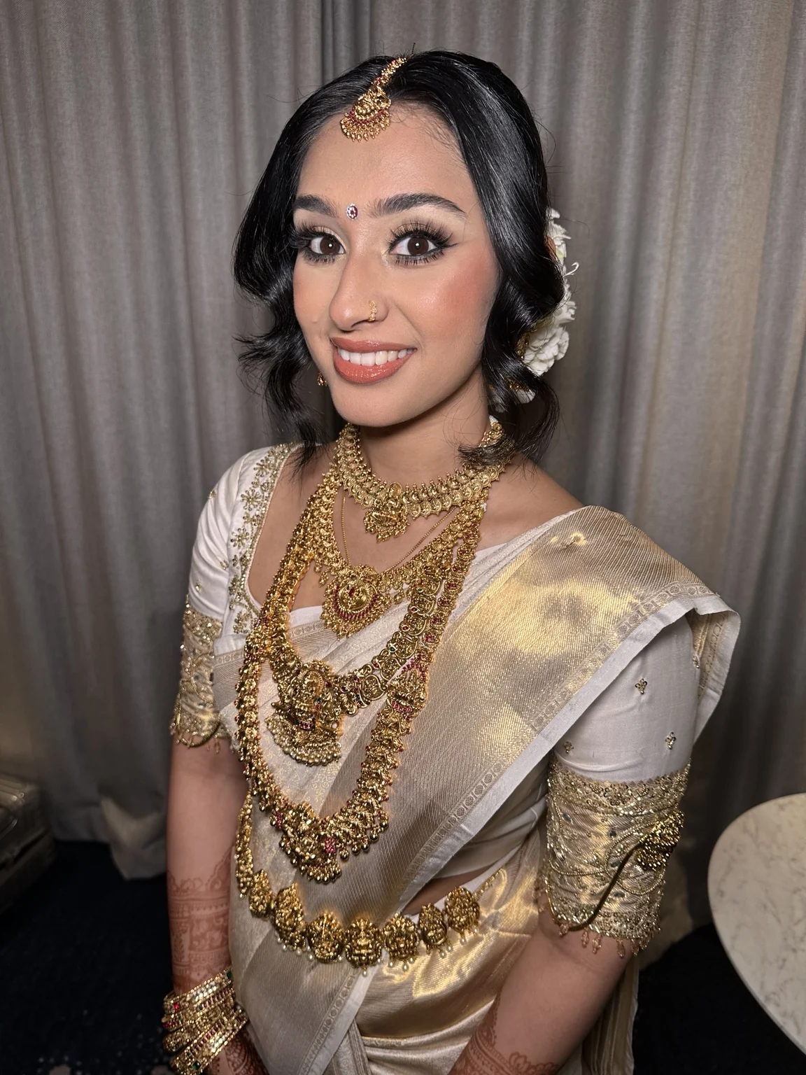 Avishma’s ivory-and-gold wedding styling by Heera, with luminous makeup, softly framed hair and gold jewellery