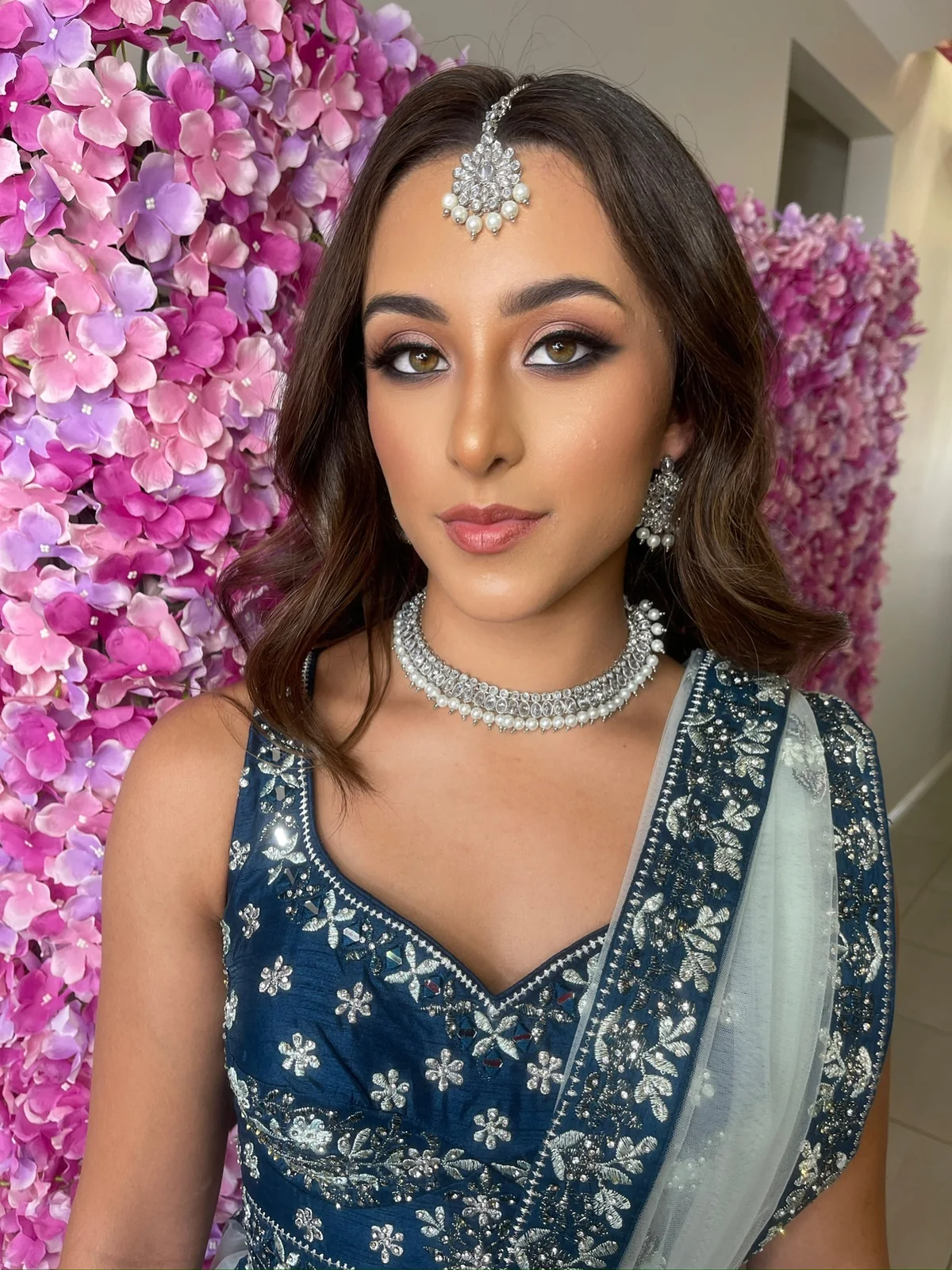Smoky eye definition, warm lips and jewellery against a blue outfit
