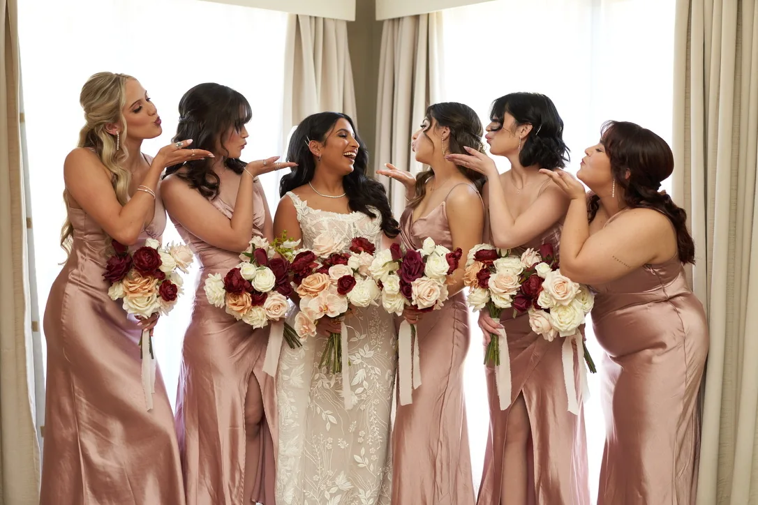 Bride and loved ones in blush gowns sharing a wedding-day moment
