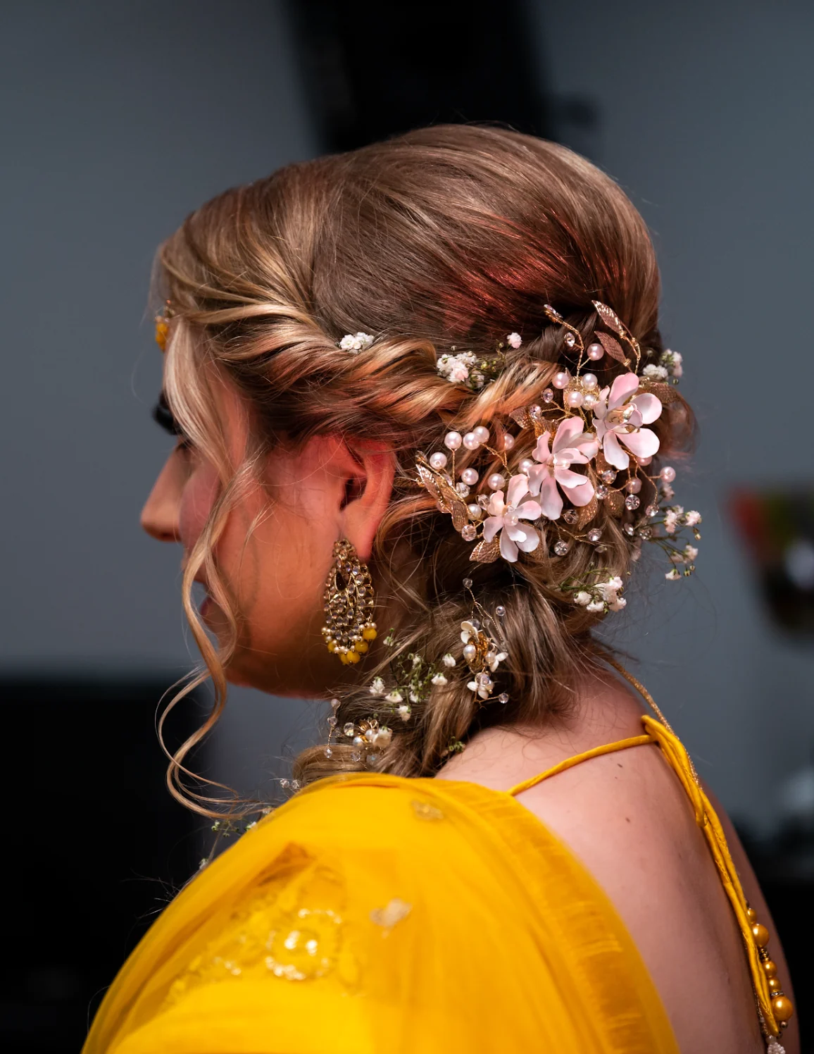 Textured bridal updo with woven twists, delicate flowers and pearl hair jewellery, styled by Heera