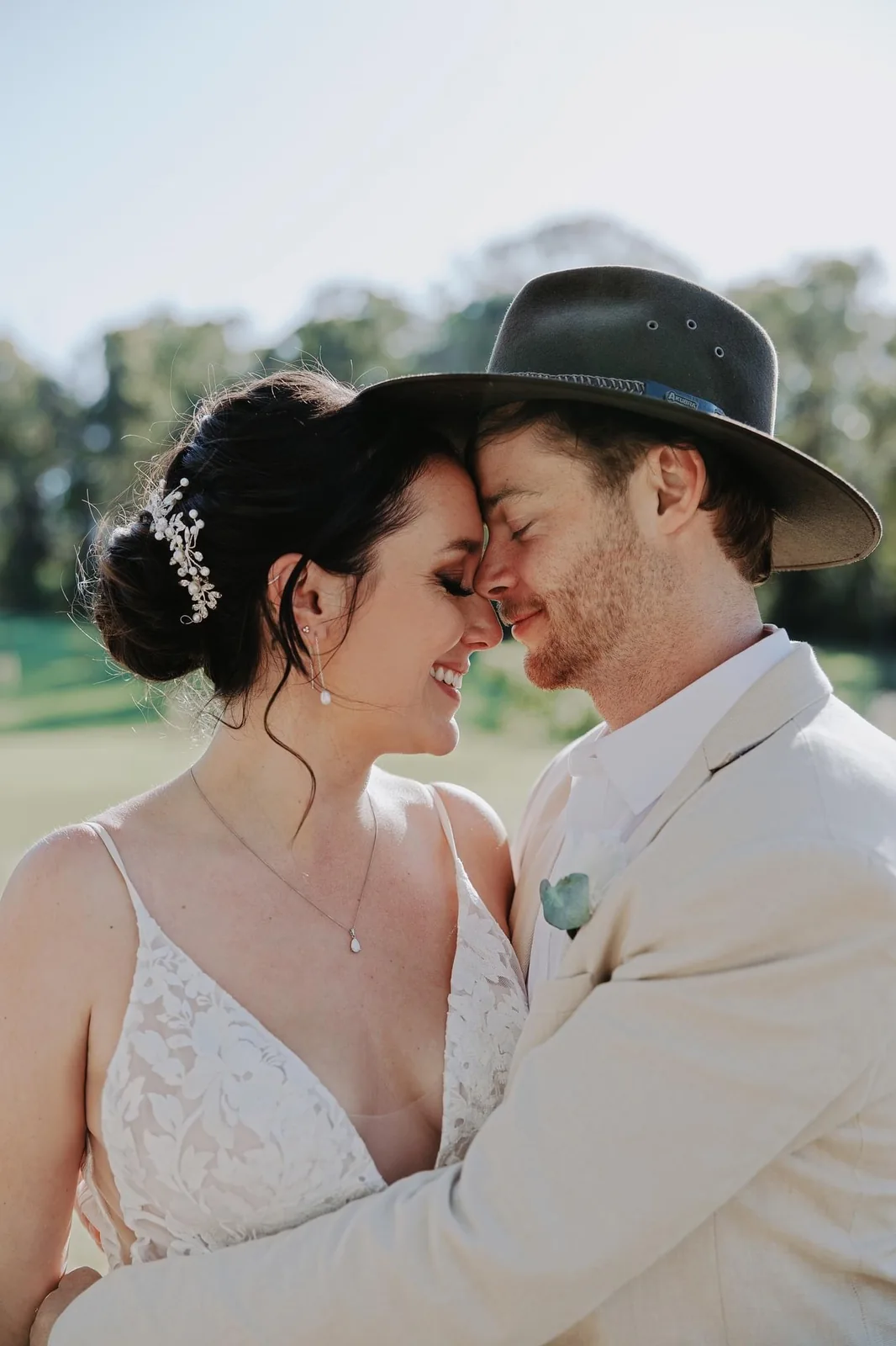 White-gown bride with a softly framed updo and her partner outdoors
