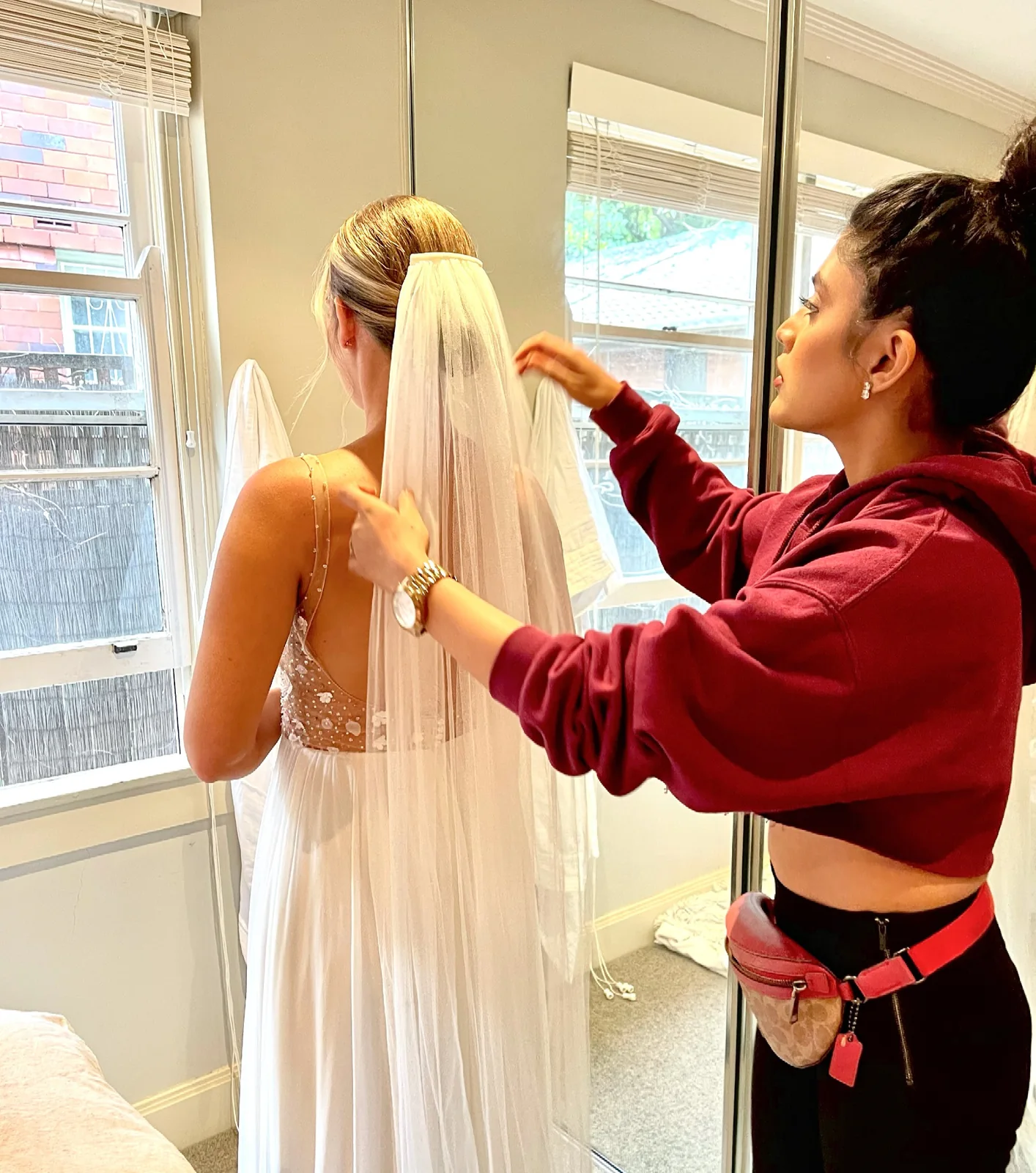 Heera positioning a veil over a blonde bridal hairstyle
