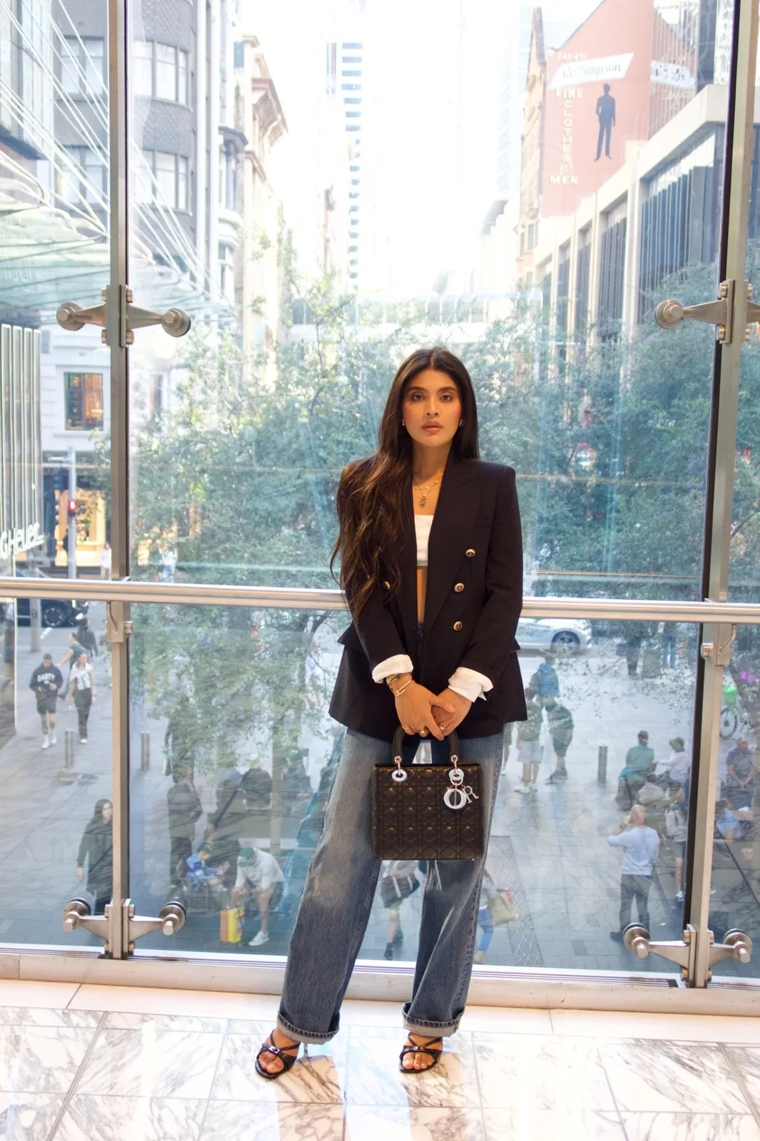 Heera, Sydney bridal hair and makeup artist, standing against a city backdrop