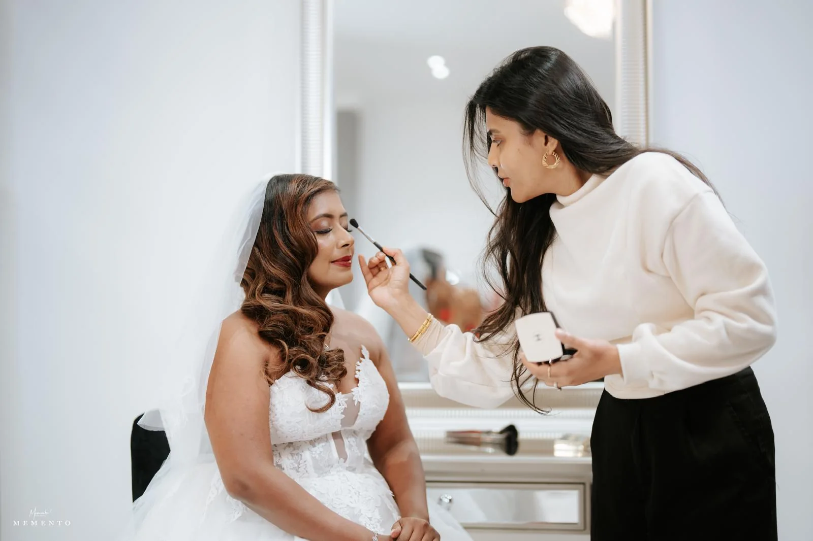 Heera refining eye makeup for a white-gown bride with a veil and softly waved hair