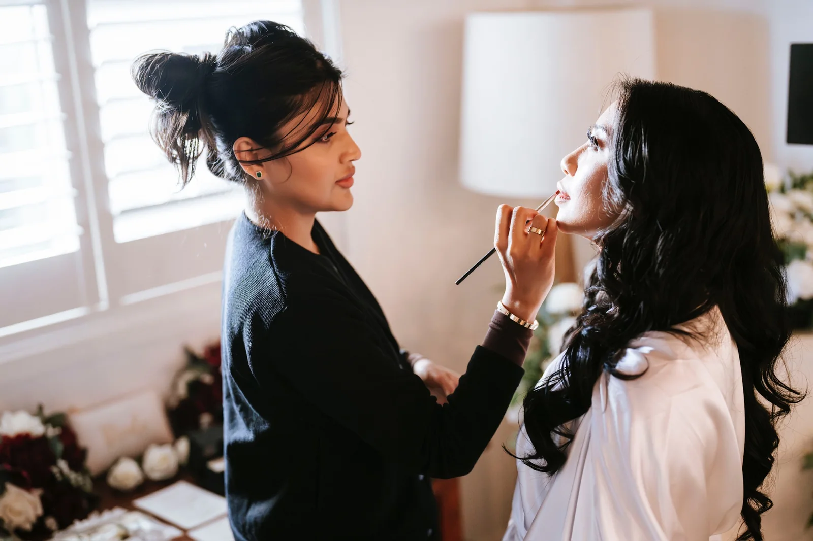Heera refining a bride’s lip colour as they prepare together
