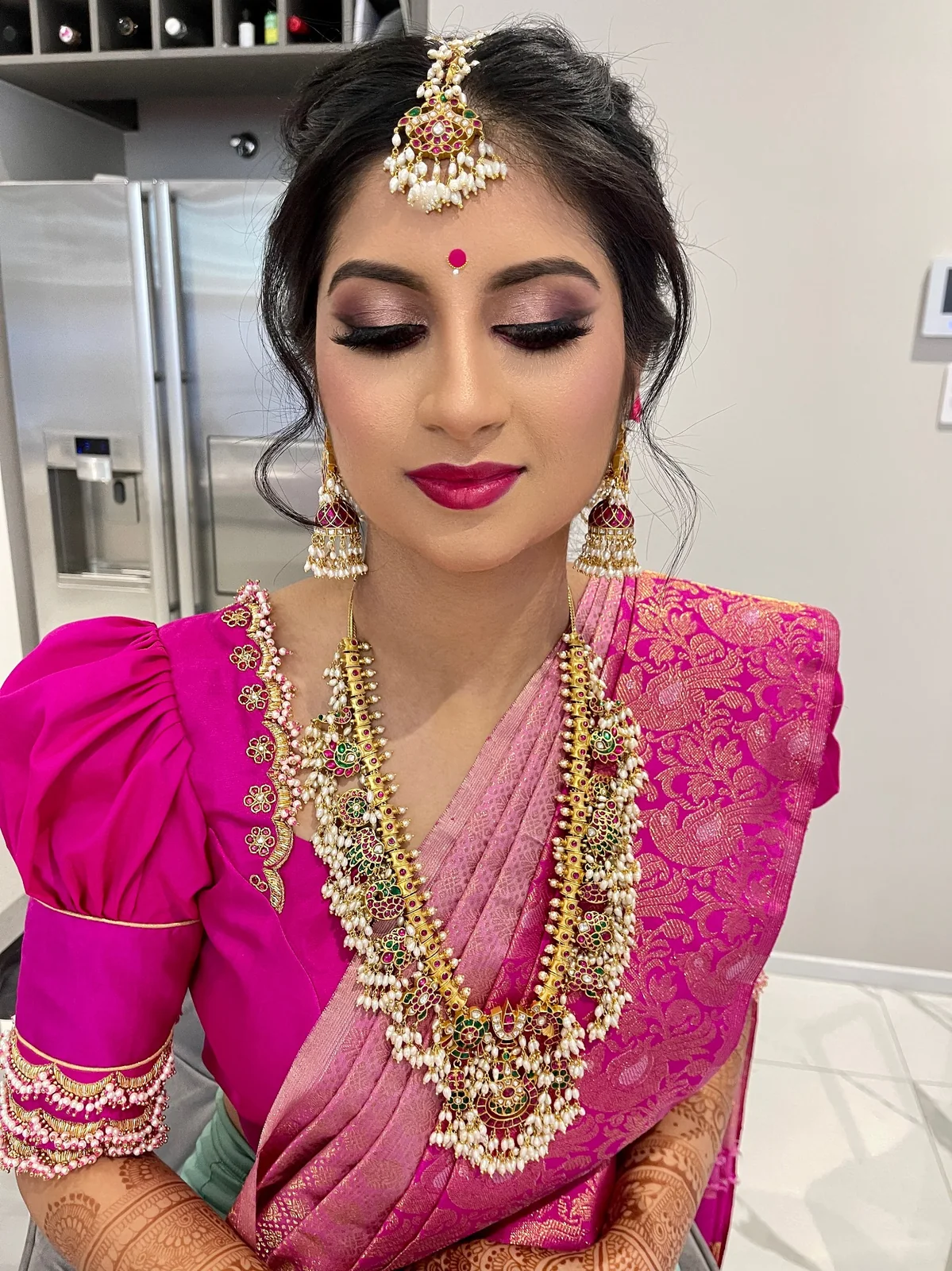 A pink saree, gold bridal jewellery, defined eyes and a bright lip