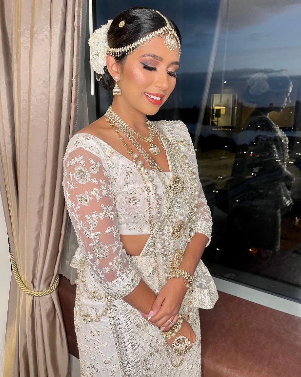 Sri Lankan bride with a sleek floral updo, ivory bridal outfit and traditional jewellery