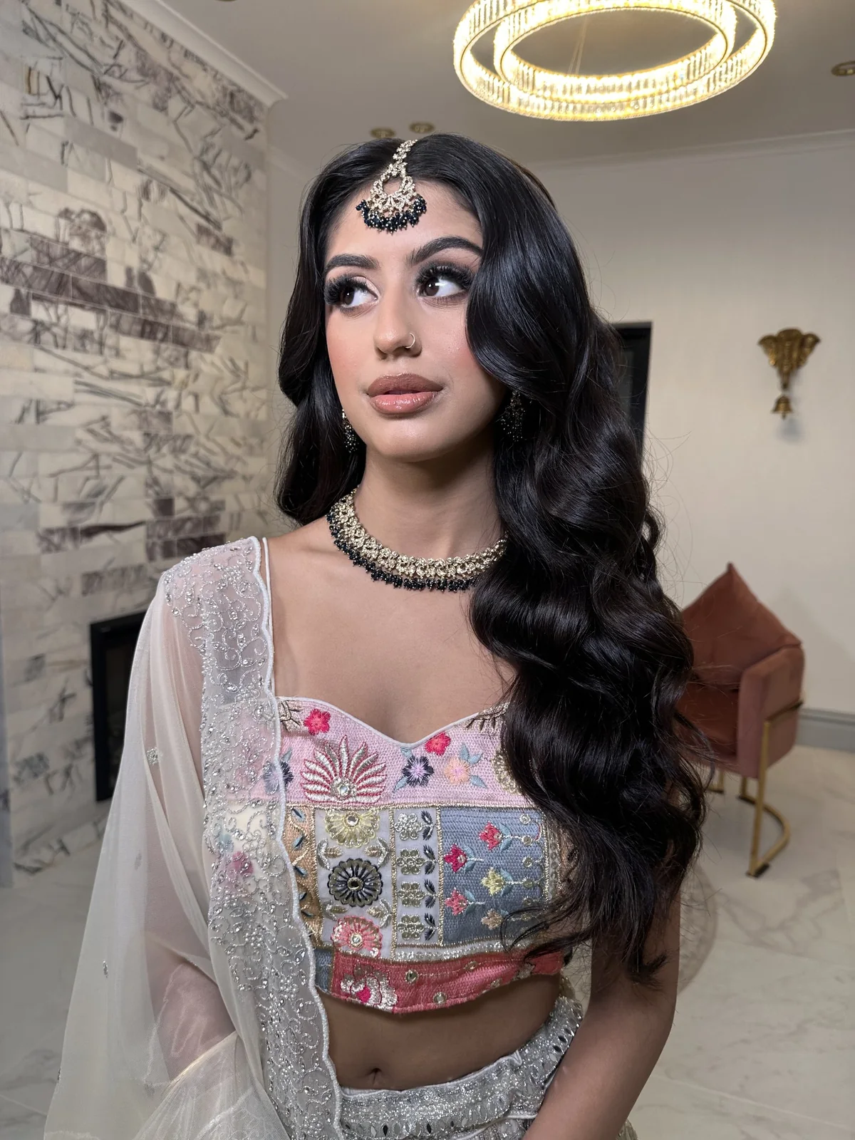 Glossy sculpted Hollywood waves, defined eyes and traditional jewellery with a pastel embroidered outfit