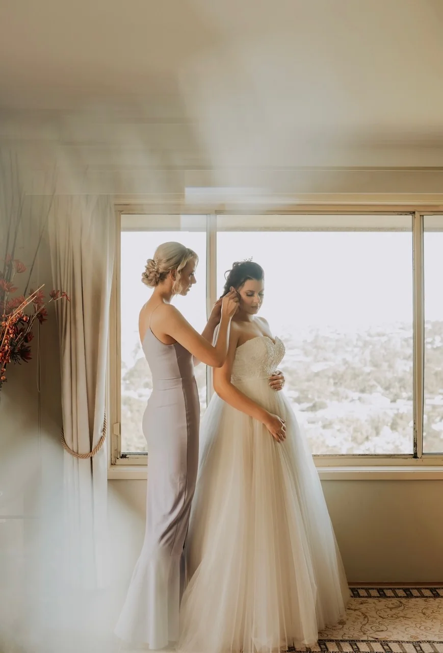 A bride and a loved one together beside the window