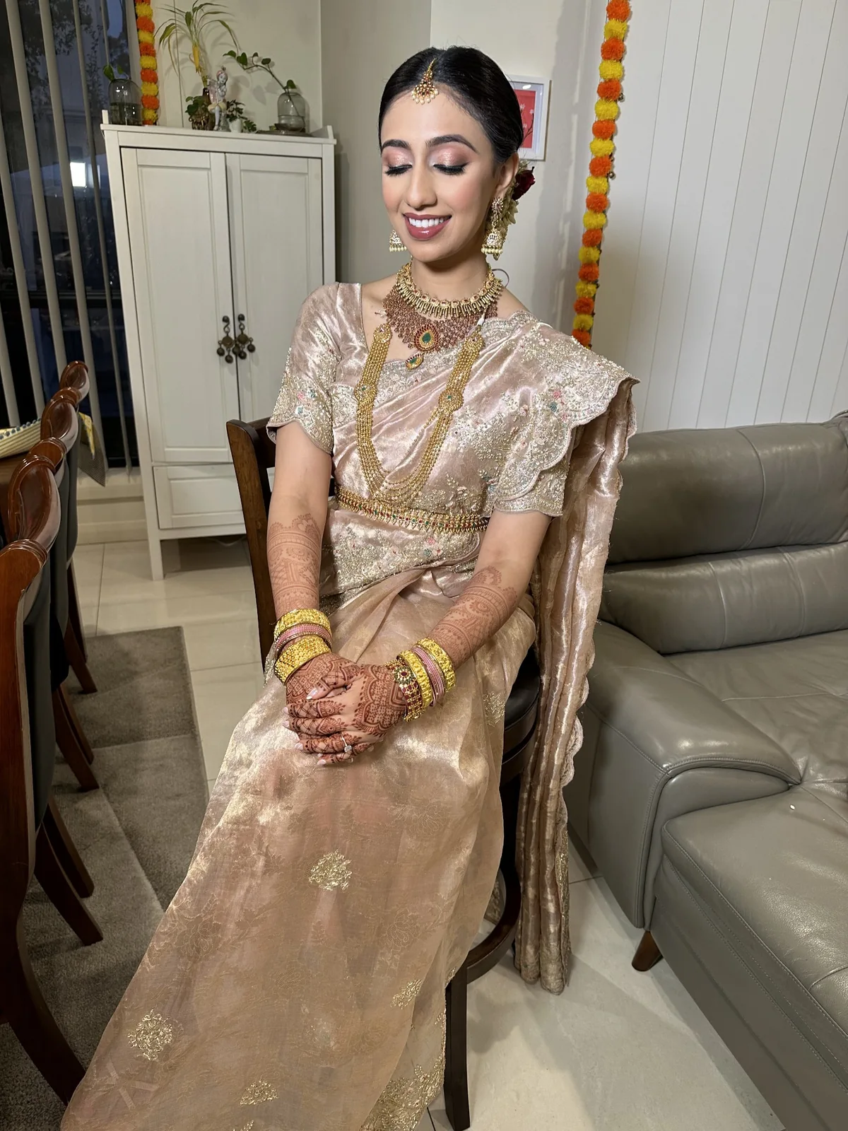 Bride in a gold silk saree with a smooth updo, traditional jewellery and softly defined makeup