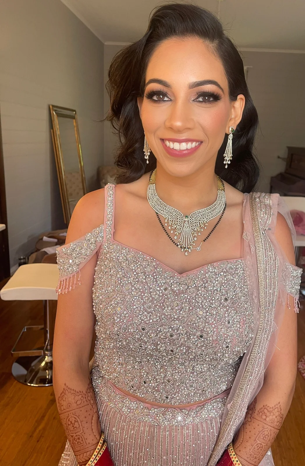 Smiling client with a textured updo, silver outfit and softly defined makeup