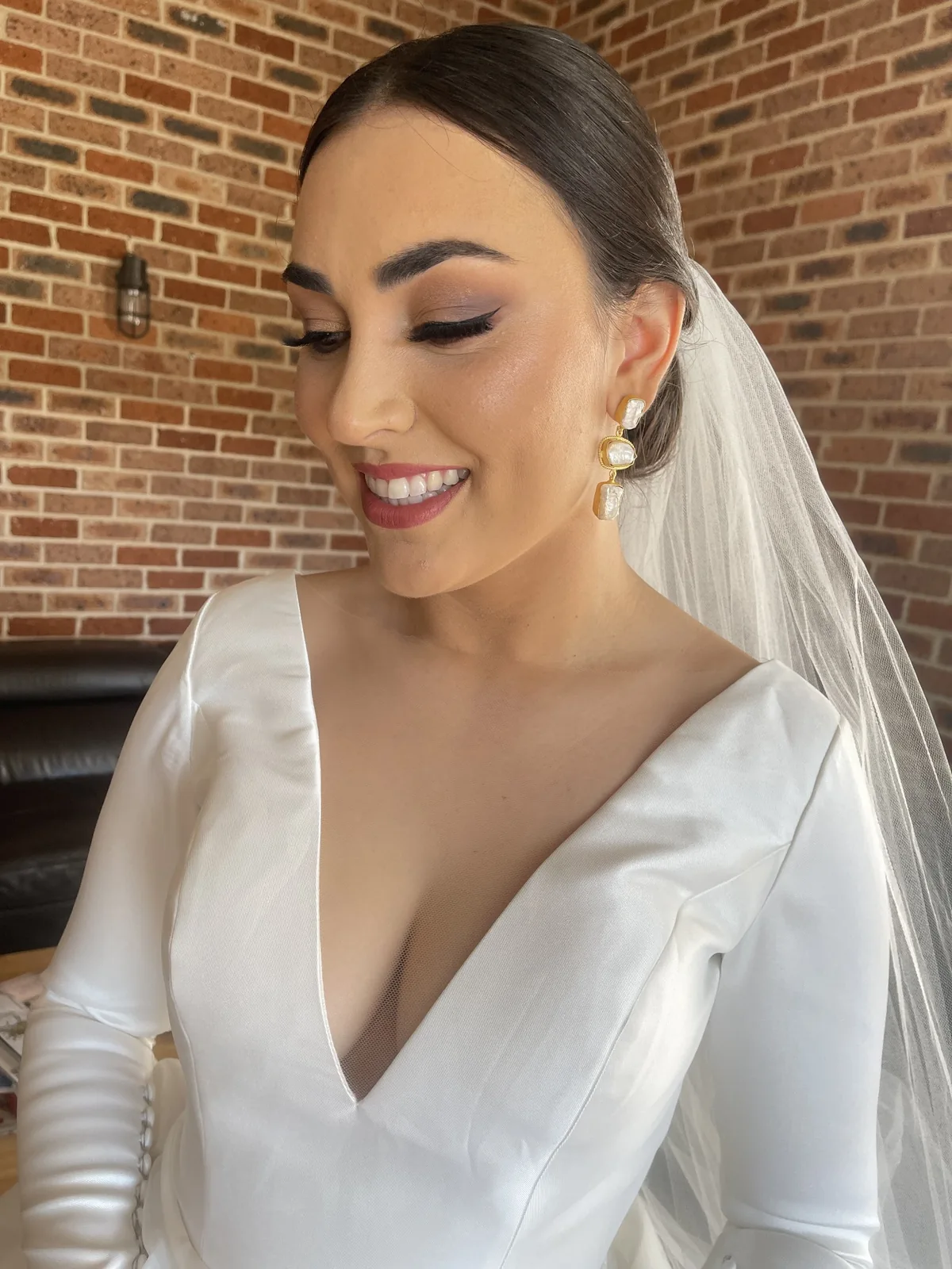 Smiling bride with softly defined eyes, a textured updo and a veil