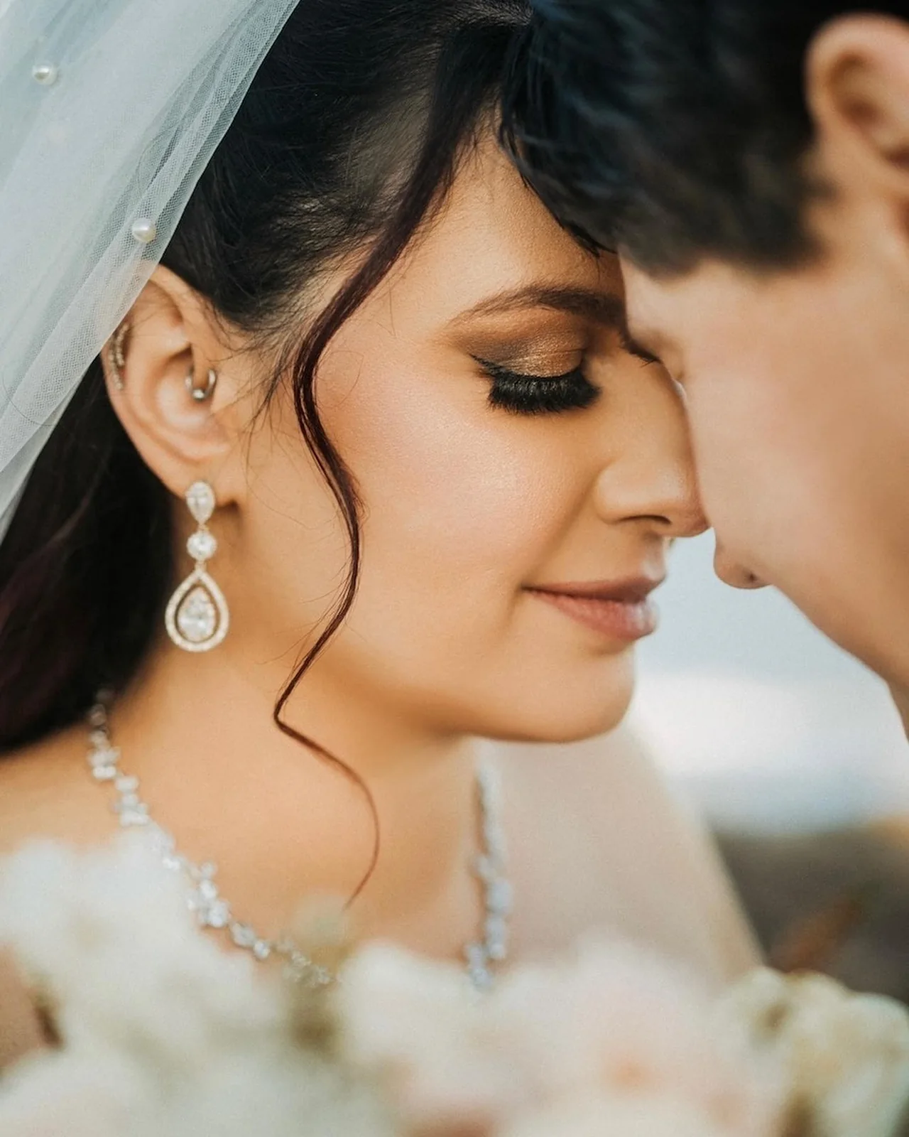 Bride in a white gown and delicate veil with warm eye definition and softly framed hair