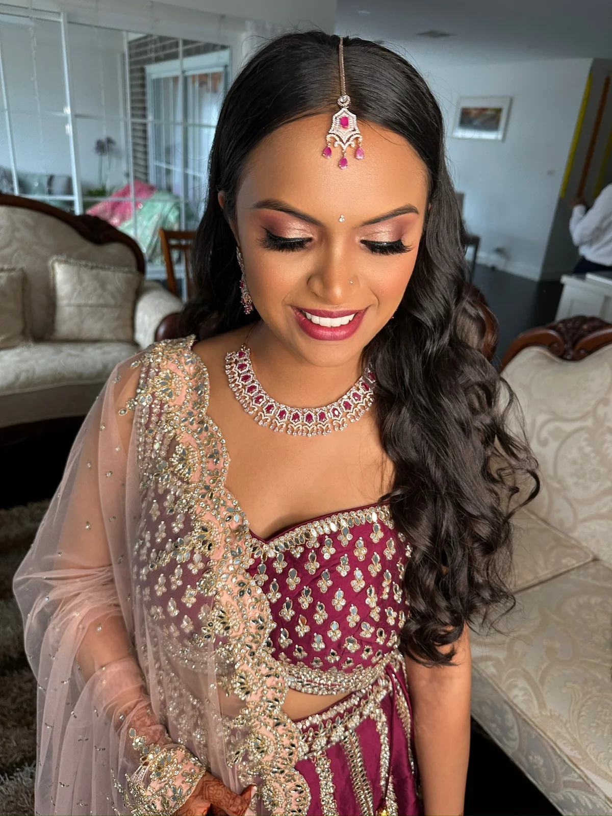 Bride with loose waves, softly defined makeup and a pink embroidered bridal outfit