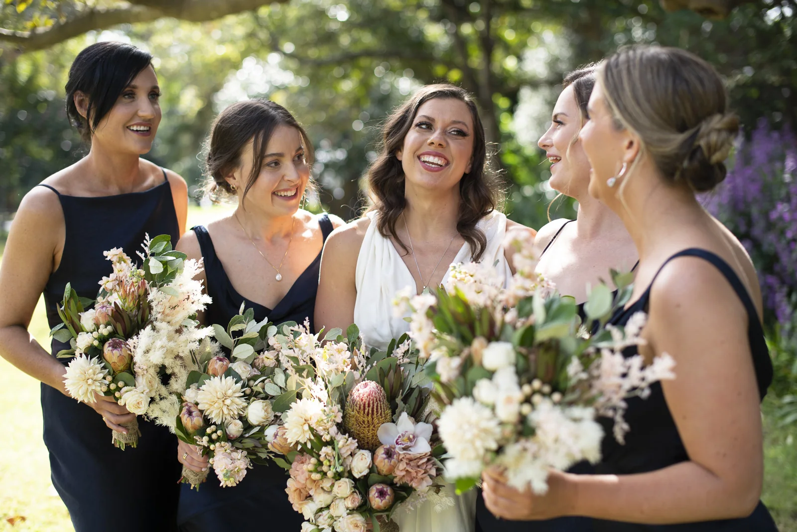 A white-gown bride, her bridal party and softly coloured bouquets
