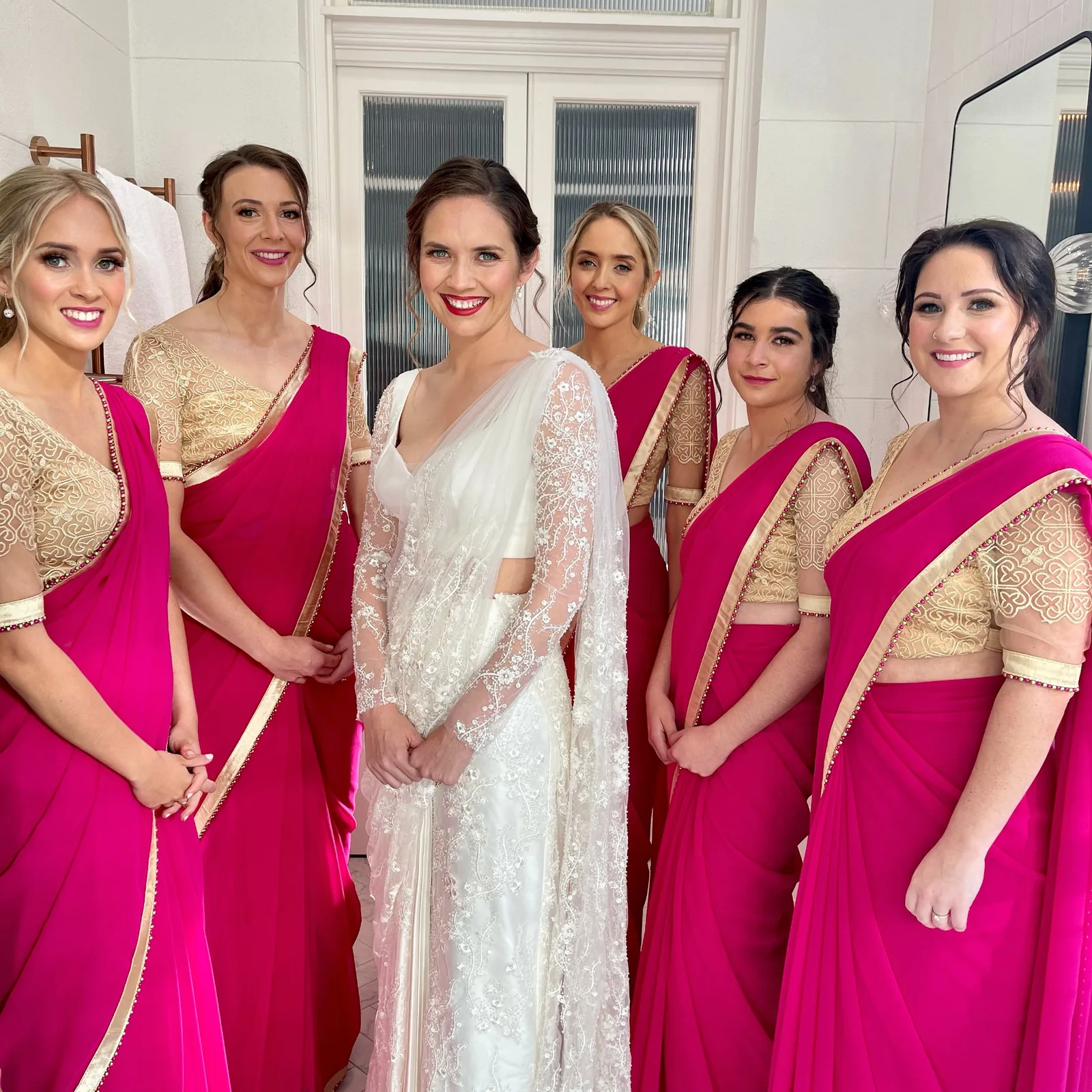 White-gown bride with loved ones in pink sarees