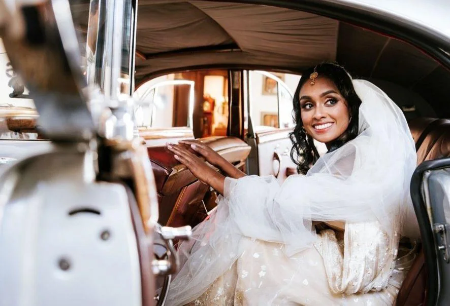 A white gown, a soft veil and defined eyes in a vintage wedding car