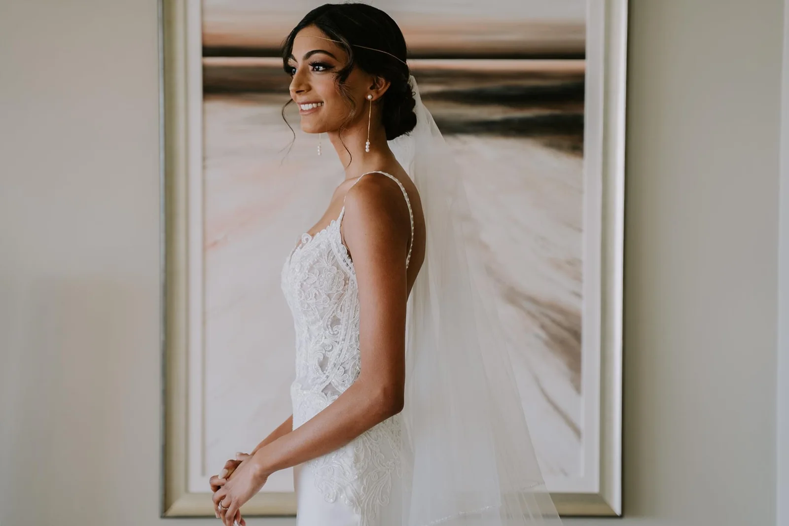 White-gown bride with luminous makeup, a softly textured updo and a delicate veil