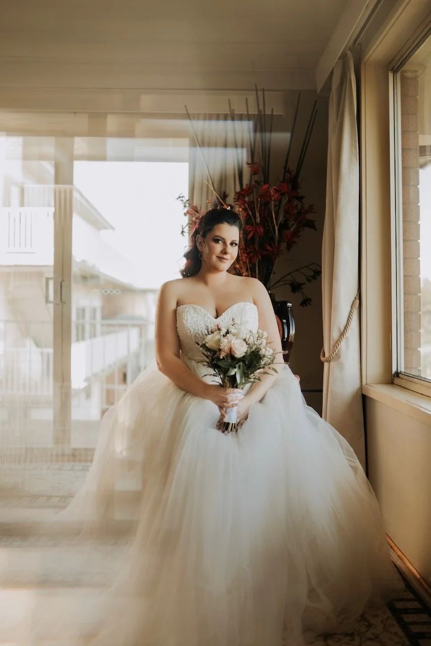 A full white gown, bridal bouquet and softly styled hair