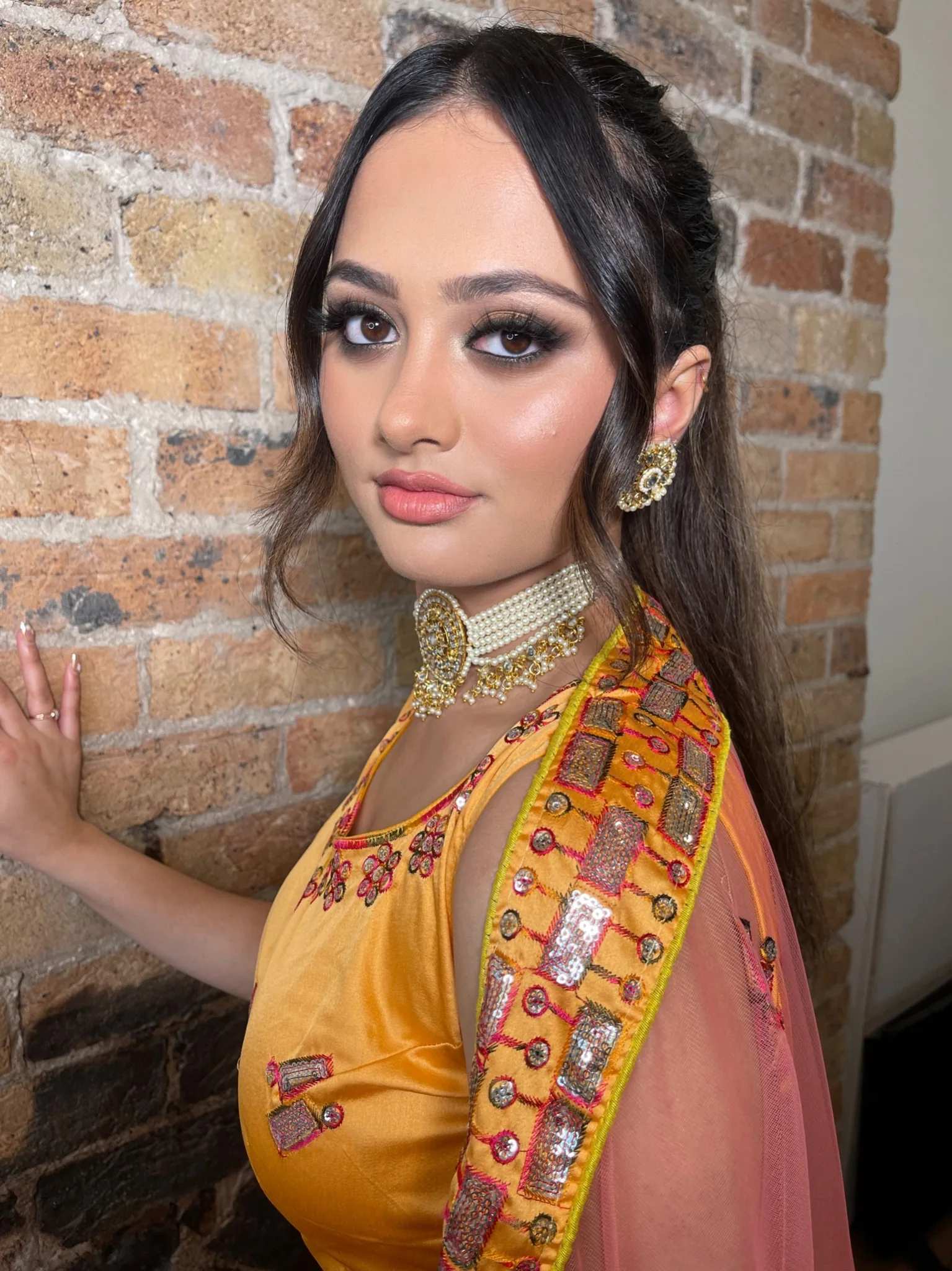 Client in a yellow embroidered outfit with smoky eye definition, soft face framing and a choker