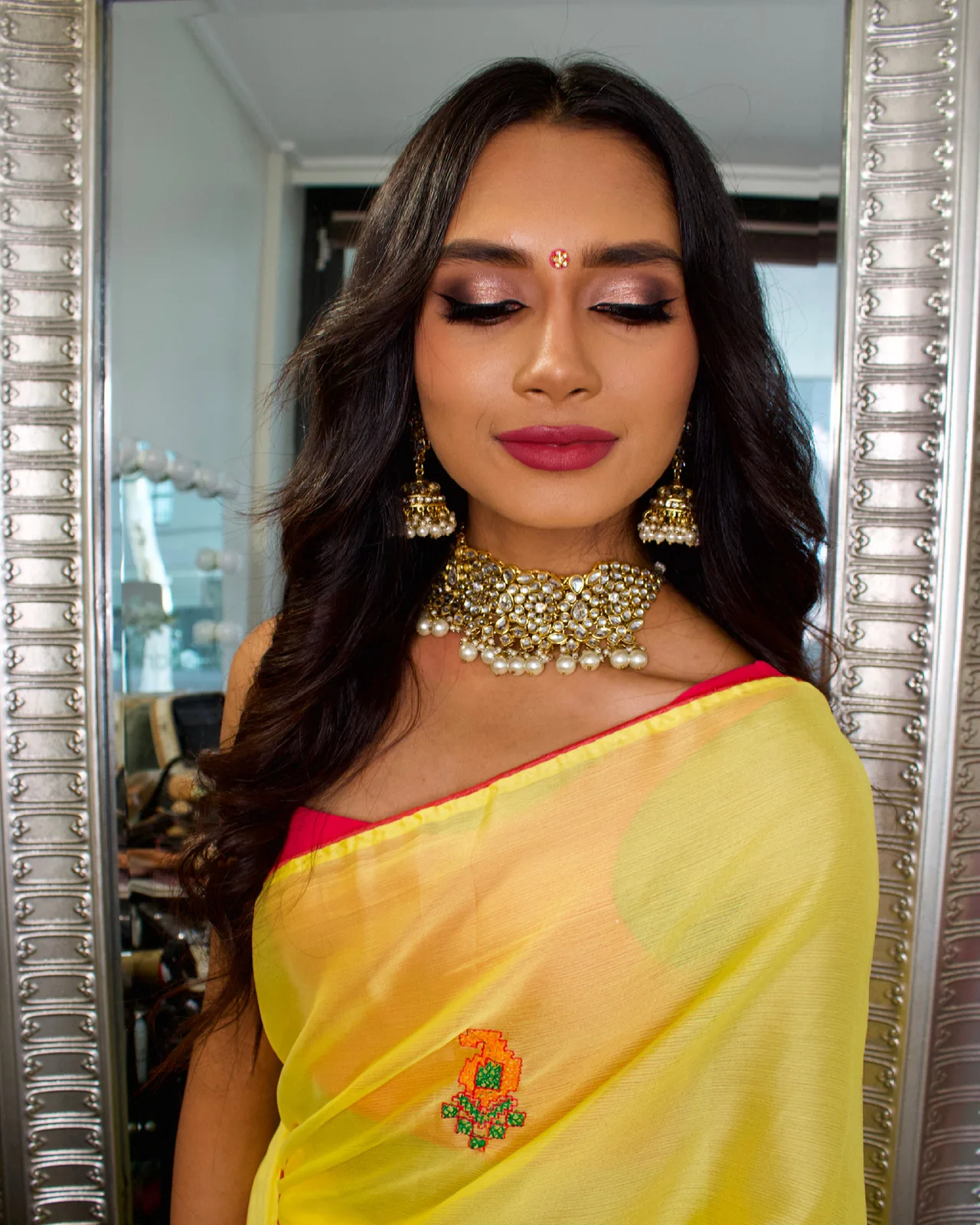 Heera’s warm eye definition, softly waved hair and rose lip paired with a yellow saree